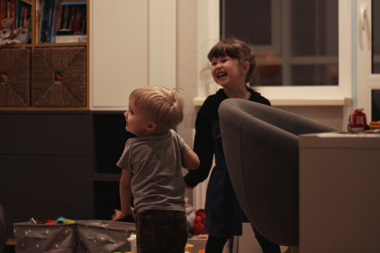 Ein kleiner Junge und ein kleines Mädchen spielen zusammen in der Nähe eines Spielzeugregals.
